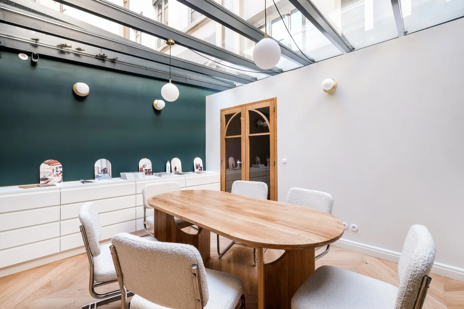 Salle de réunion sous verrière : table ovale en bois et chaises bouclé, mur vert — Passage de Lyon
