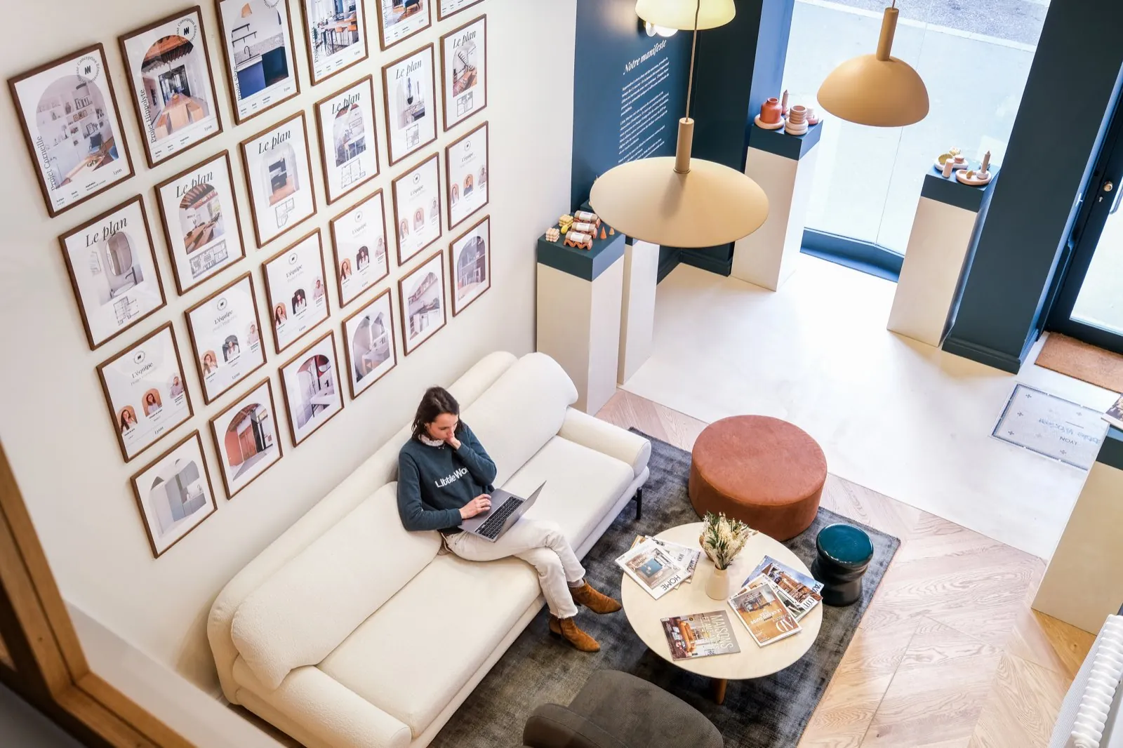 Vue plongeante sur le salon : canapé blanc, pouf terracotta et grand mur de cadres — Passage de Lyon