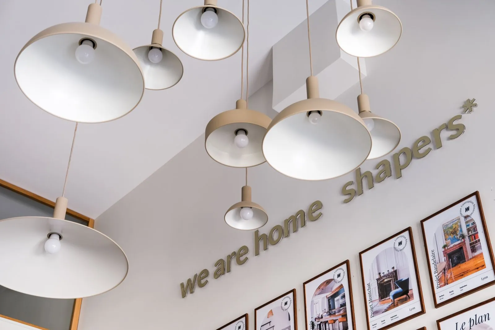 Suspensions crème et lettrage « we are home shapers » au-dessus du mur de projets — Passage de Lyon